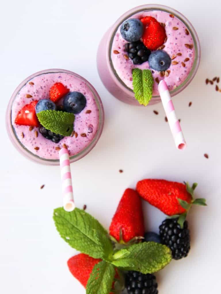 smoothies with straws and fresh strawberries and blueberries