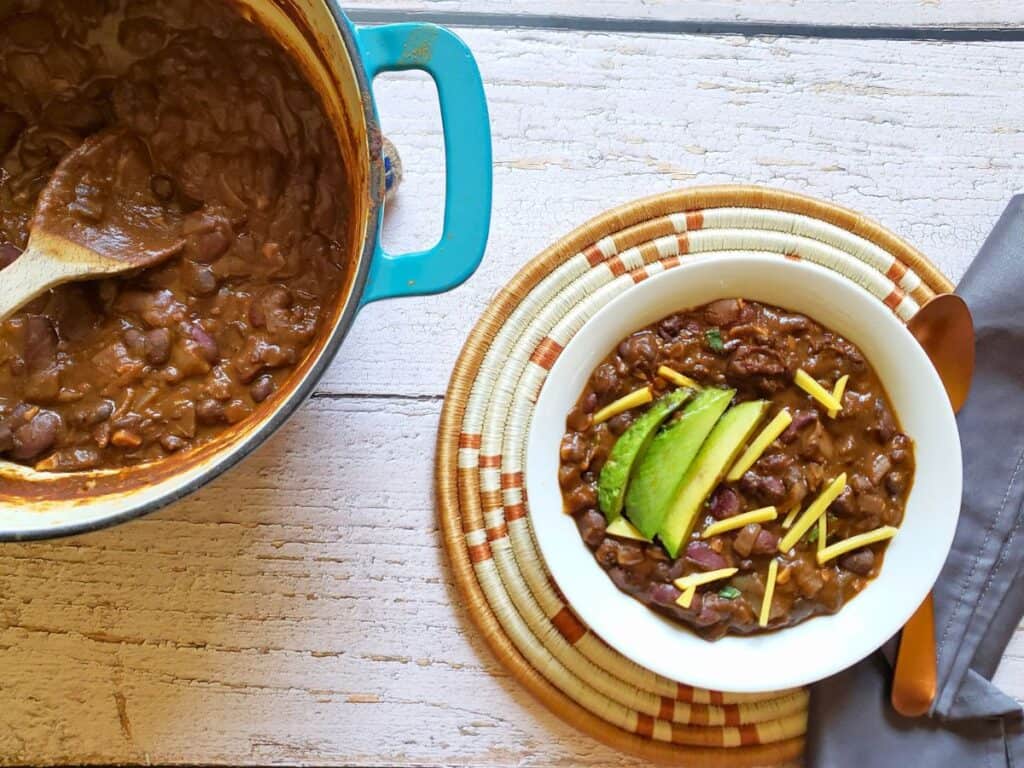 a pot and a bowl of vegan black bean chili recipe no tomatoes
