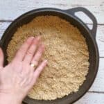 a crumble pie crust being pressed into a pie dish