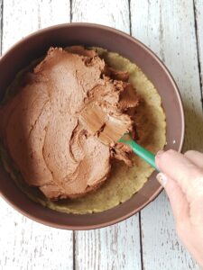 vegan gluten free cheesecake filling being spread over crust in a springform pan