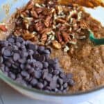 chocolate chips and nuts added to healthy vegan brownie mix in a mixing bowl