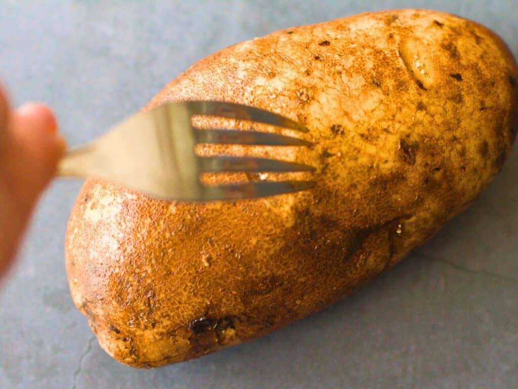 a fork being poked into a potato