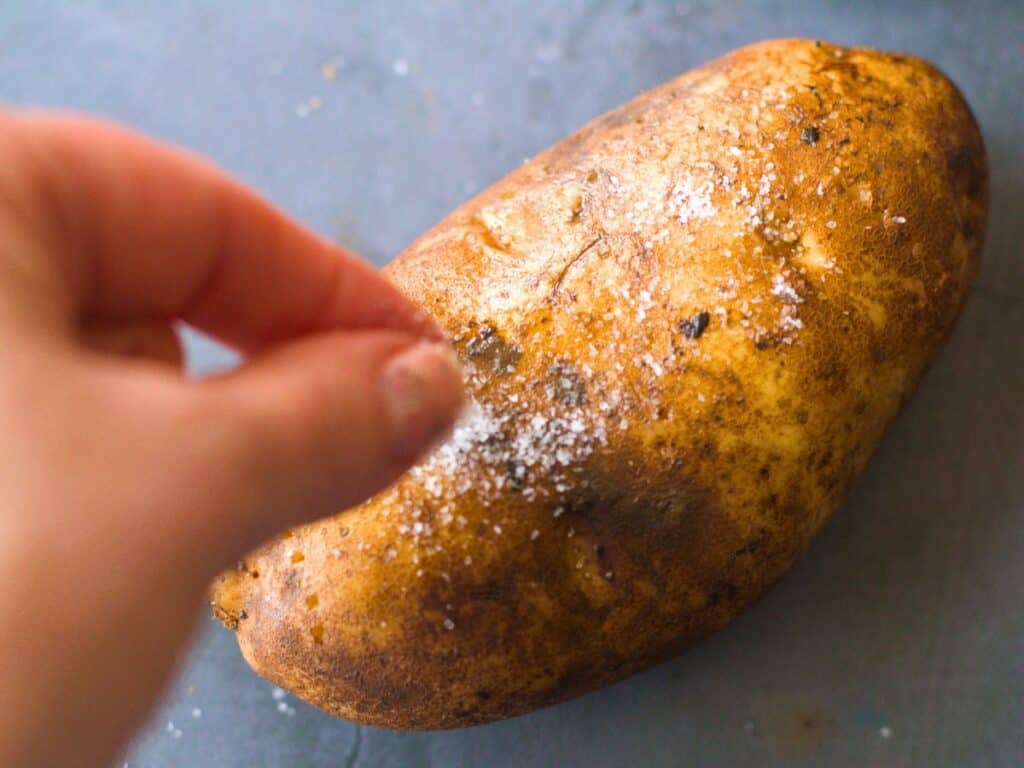 potato being sprinkled with salt