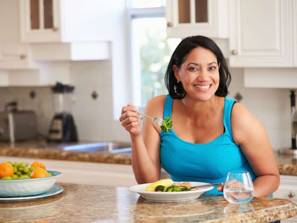 a woman holding a fork full of vegetables