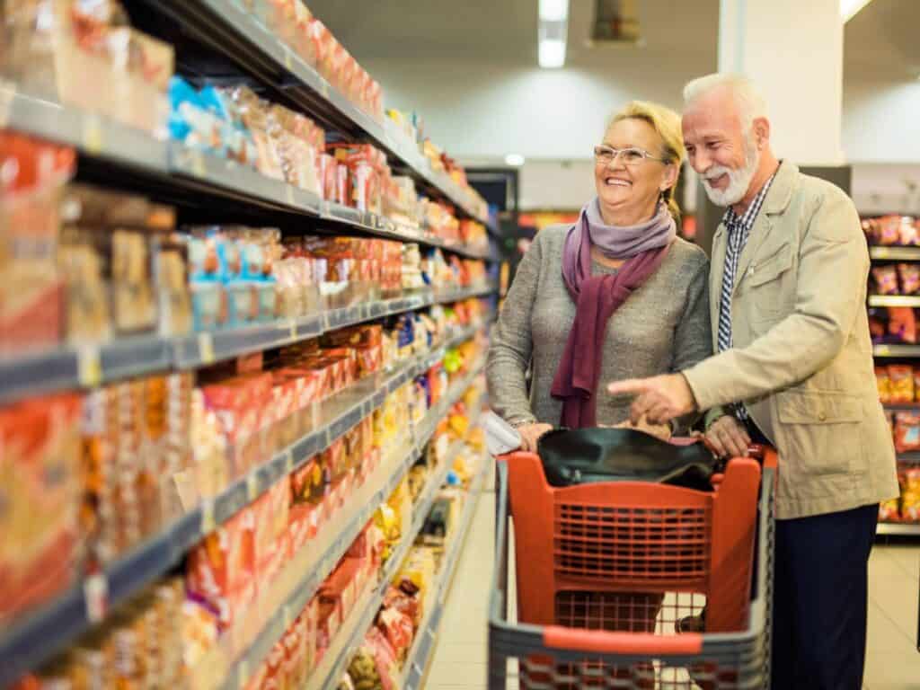 a couple shopping in a grocery store with a shopping cart
