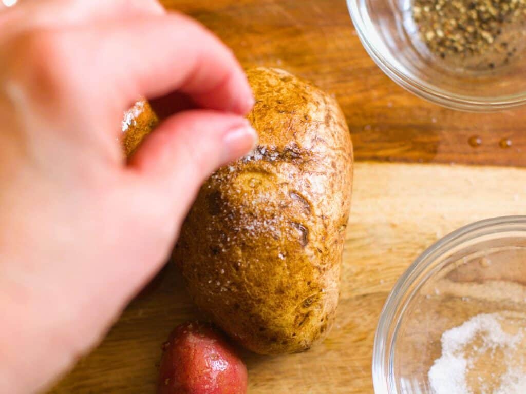 salt being sprinkled over a potato