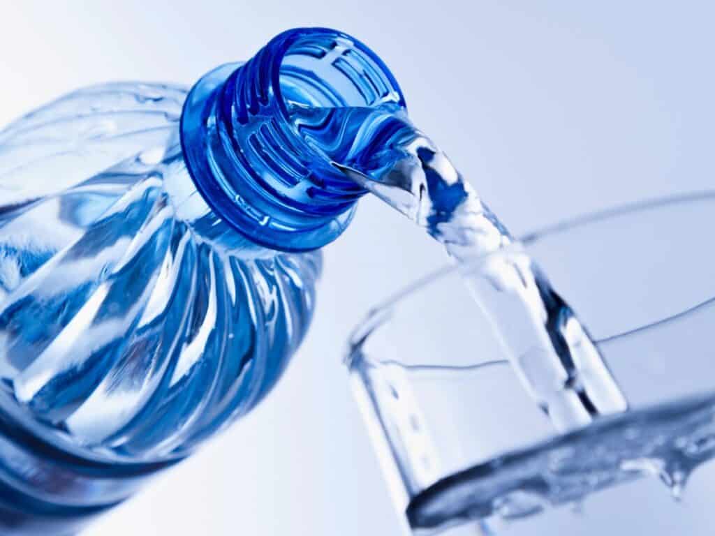 a bottle of water being poured into a glass