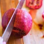 a knife cutting a pomegranate