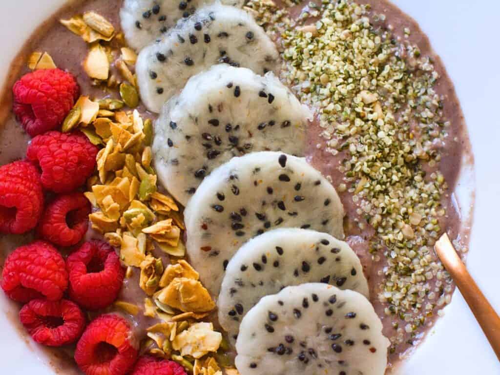 a smoothie bowl with fruit, seeds, and granola