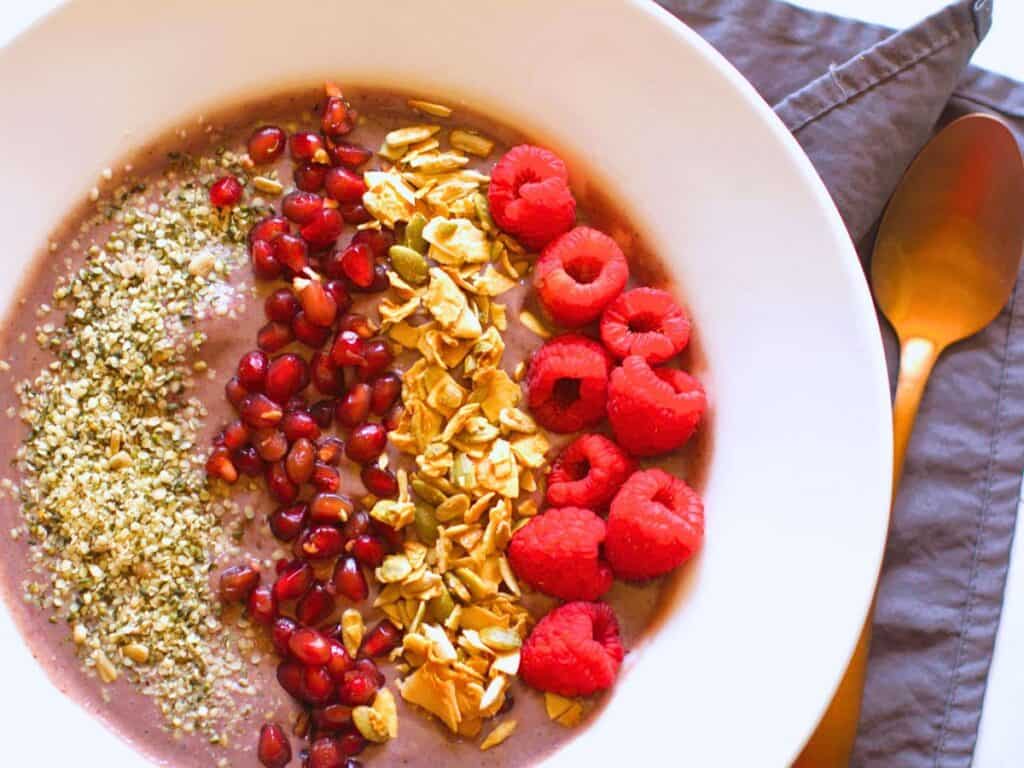 a smoothie bowl with fruit, granola, and seeds