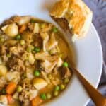 vegan stew in a white bowl with a biscuit