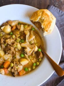 vegan stew in a white bowl with a biscuit