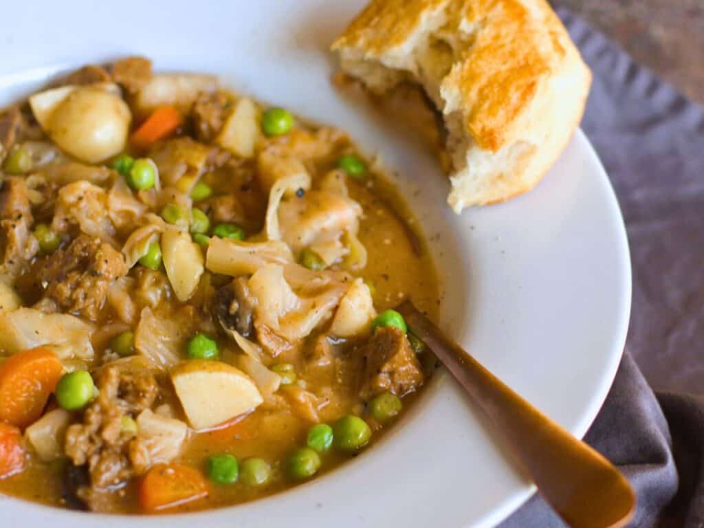 vegan Irish stew in a bowl with a biscuit
