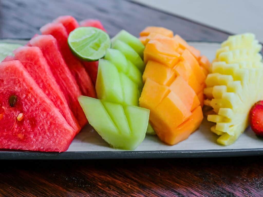 a variety of sliced melons and fruits