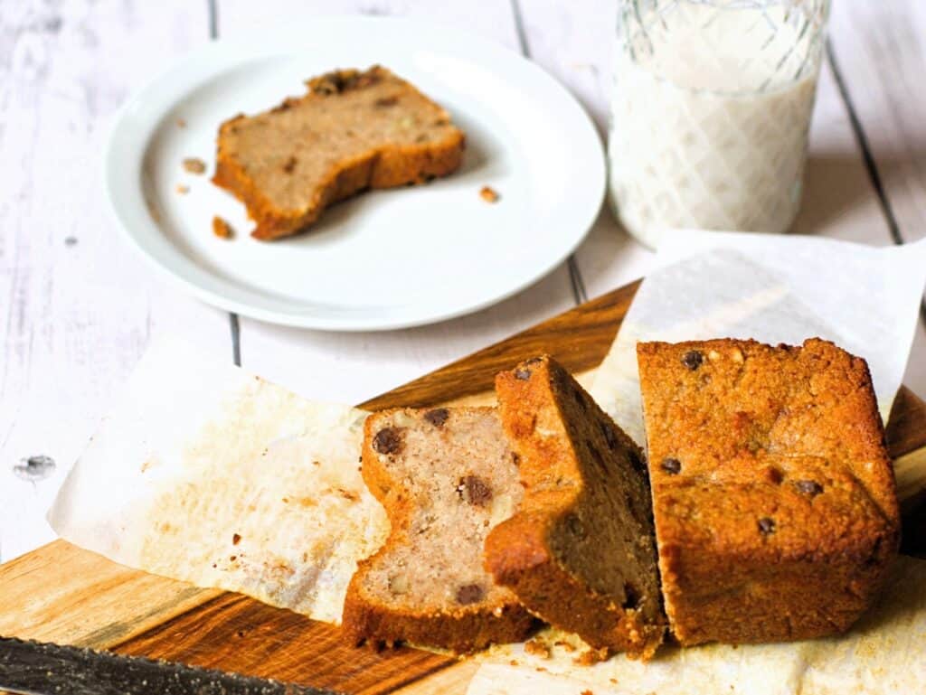 a loaf of sliced vegan keto banana bread with a slice on a plate