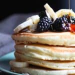a stack of pancakes with blackberries and bananas