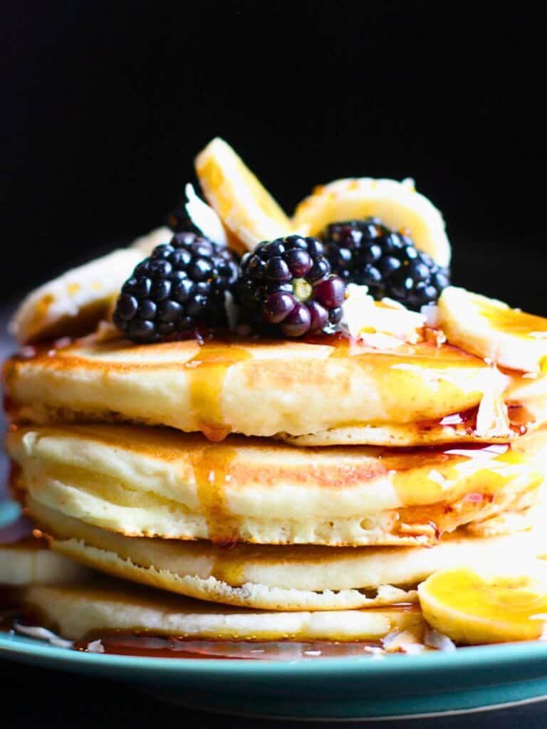 a stack of vegan pancakes with syrup and fruit