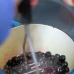 a potato masher mashing blueberries for a compote