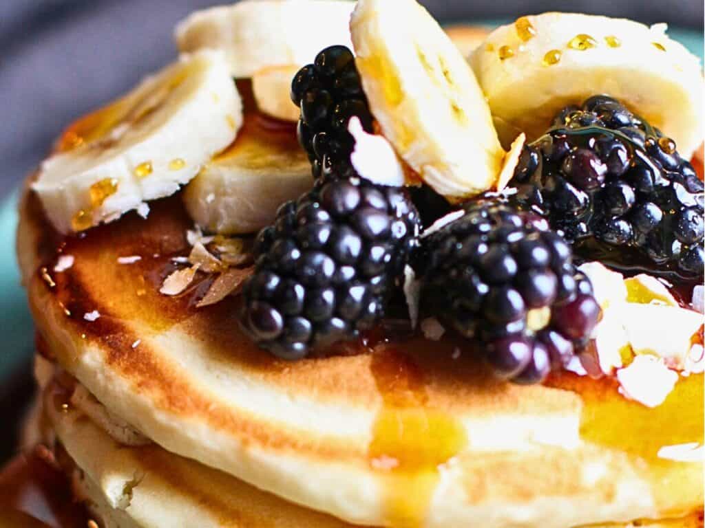 pancakes on a plate topped with fruit and syrup