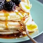 a stack of pancakes with bananas and blackberries