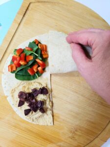 a hand folding a hummus wrap into a triangle