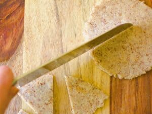 a hand with a knife cutting a keto tortilla into chips