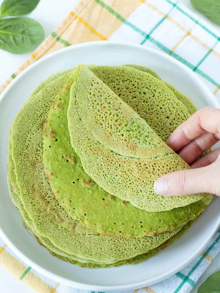 spinach tortilla being folded by hand
