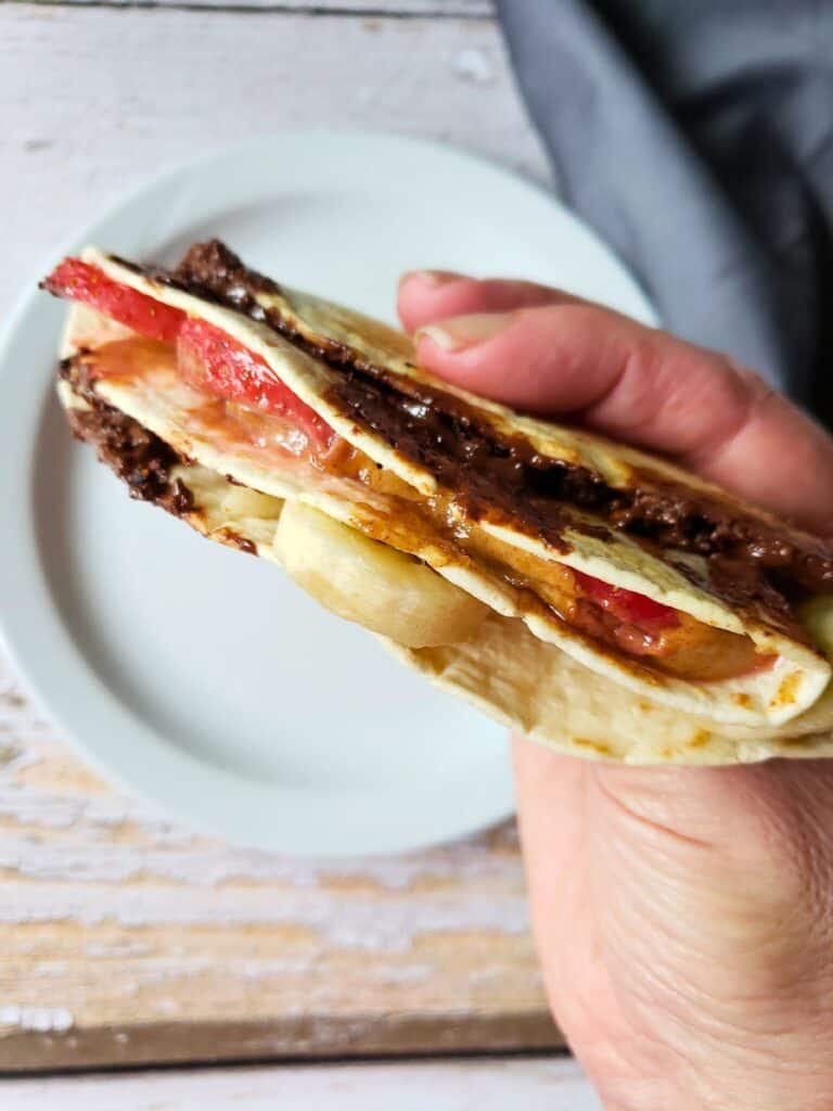 a hand holding a vegan banana dessert wrap