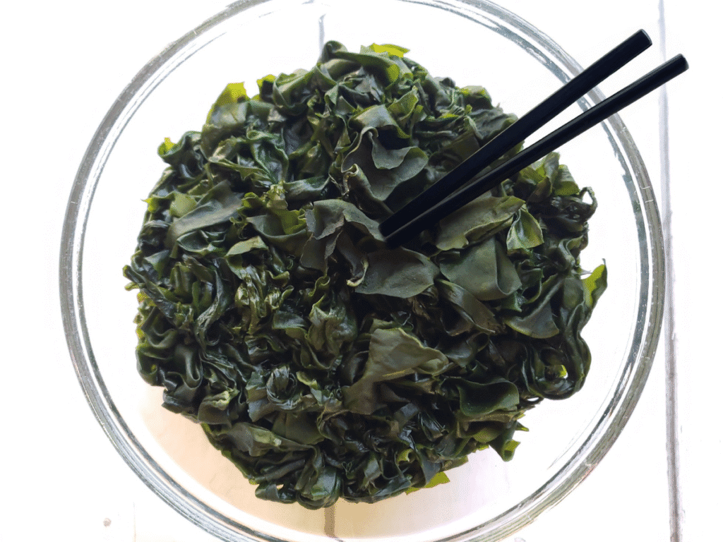 a bowl of seaweed salad with chopsticks