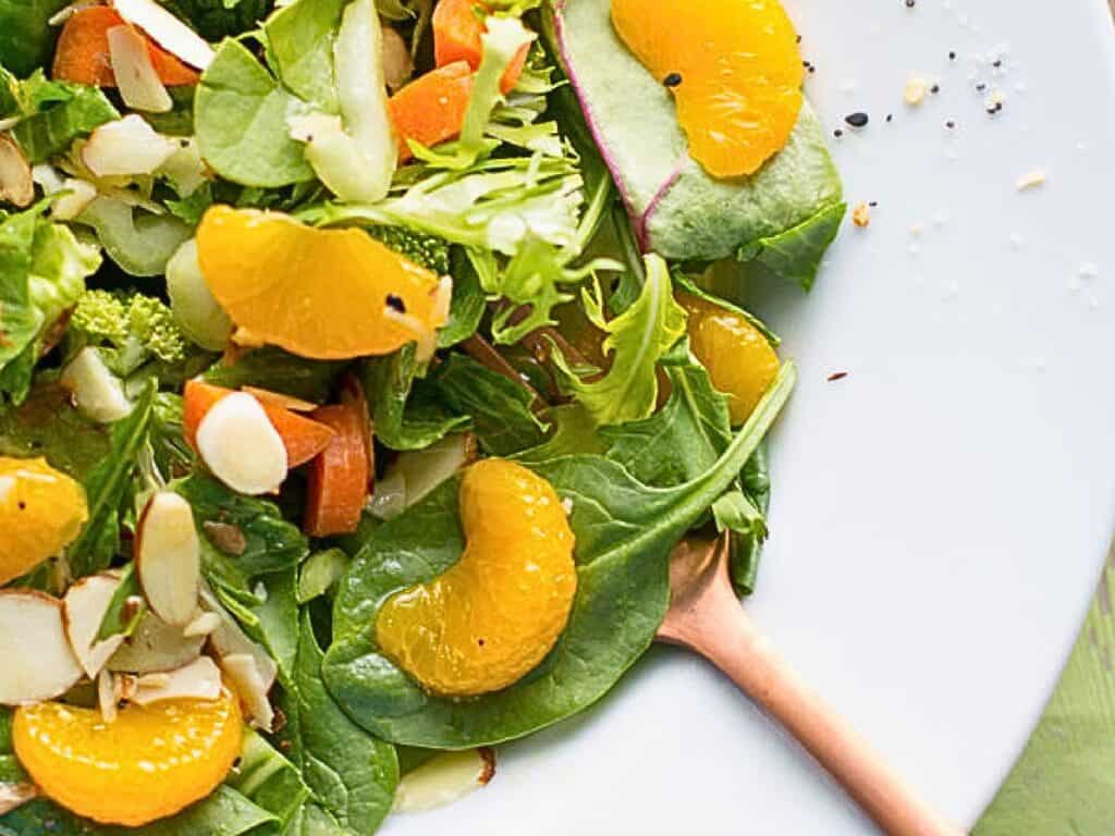 a bowl of salad with mandarin oranges and a fork