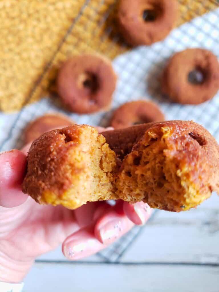 a hand holding a low calorie donut with a bite taken