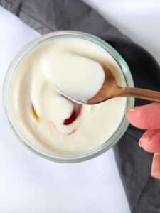 a hand holding a spoonful of vegan yogurt