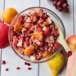 a bowl of fruit salad with a wooden spoon