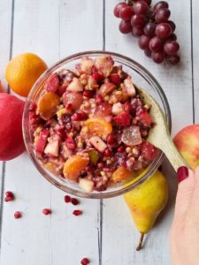 a bowl of fruit salad with a wooden spoon