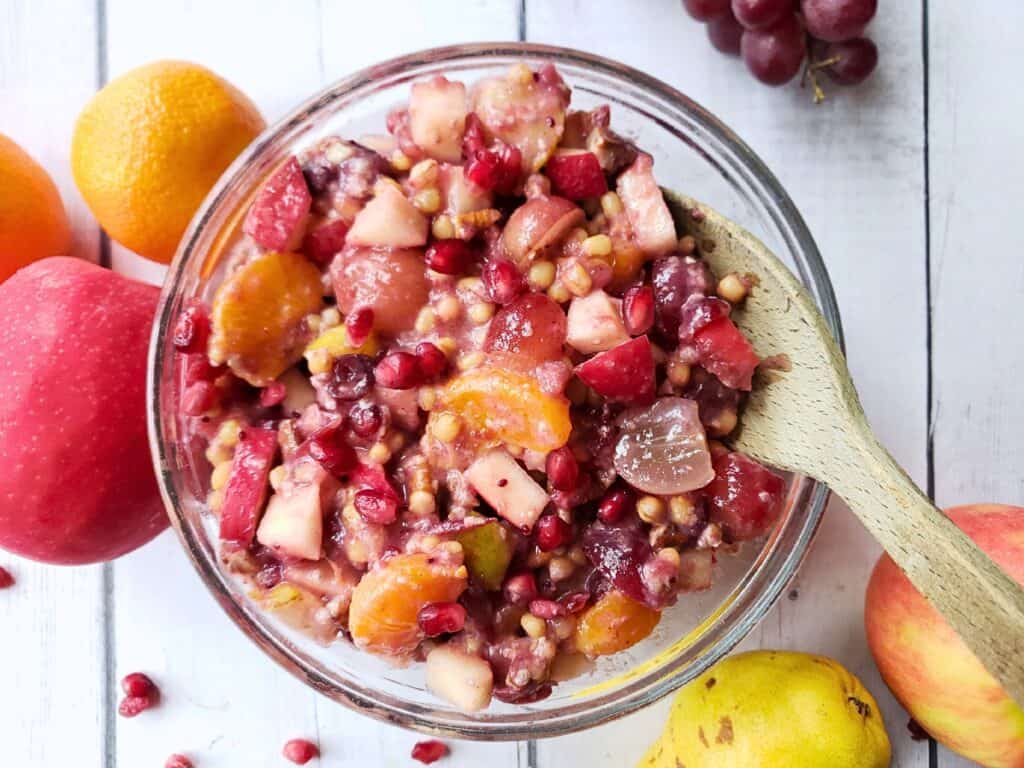 a bowl of fall fruit salad with a wooden spoon