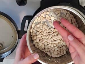 a hand sifting through white beans