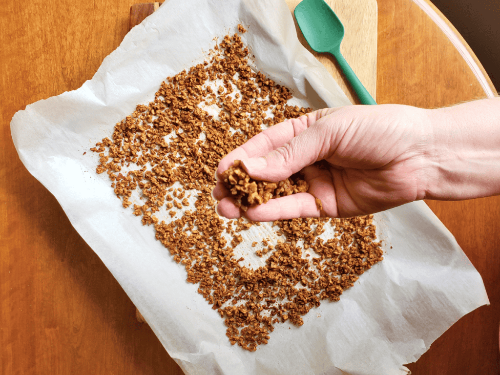 a hand holding vegan bacon bits over a pan of tvp bacon bits