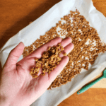 a hand holding vegan bacon bits over a pan of plant based bacon bits